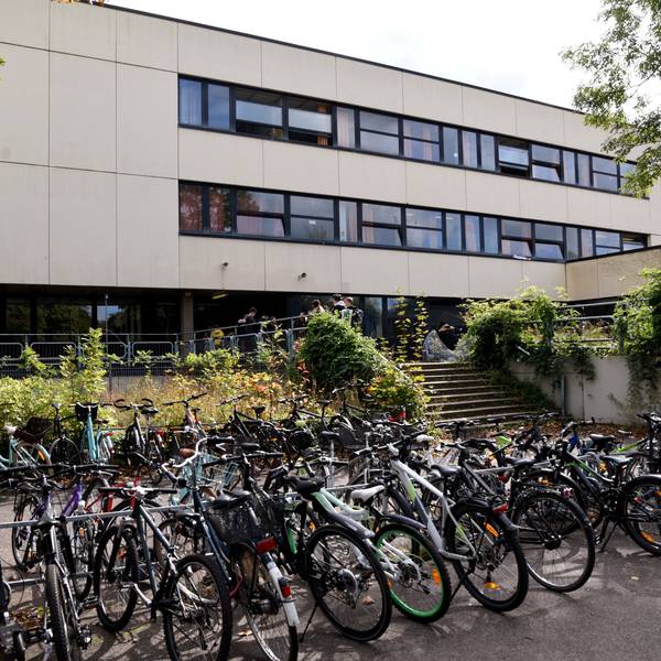 Vor einem Schulgebäude stehen viele Fahrräder.