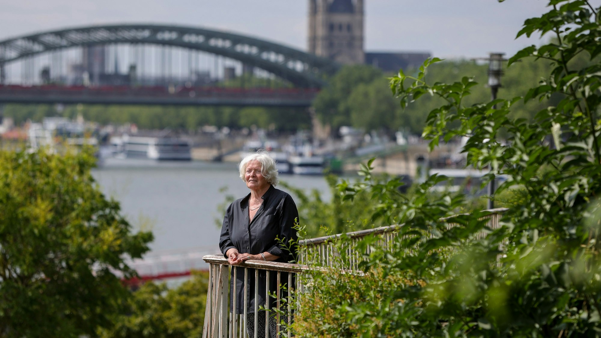 Eine Frau steht an einem Geländer und schaut auf den Rhein.