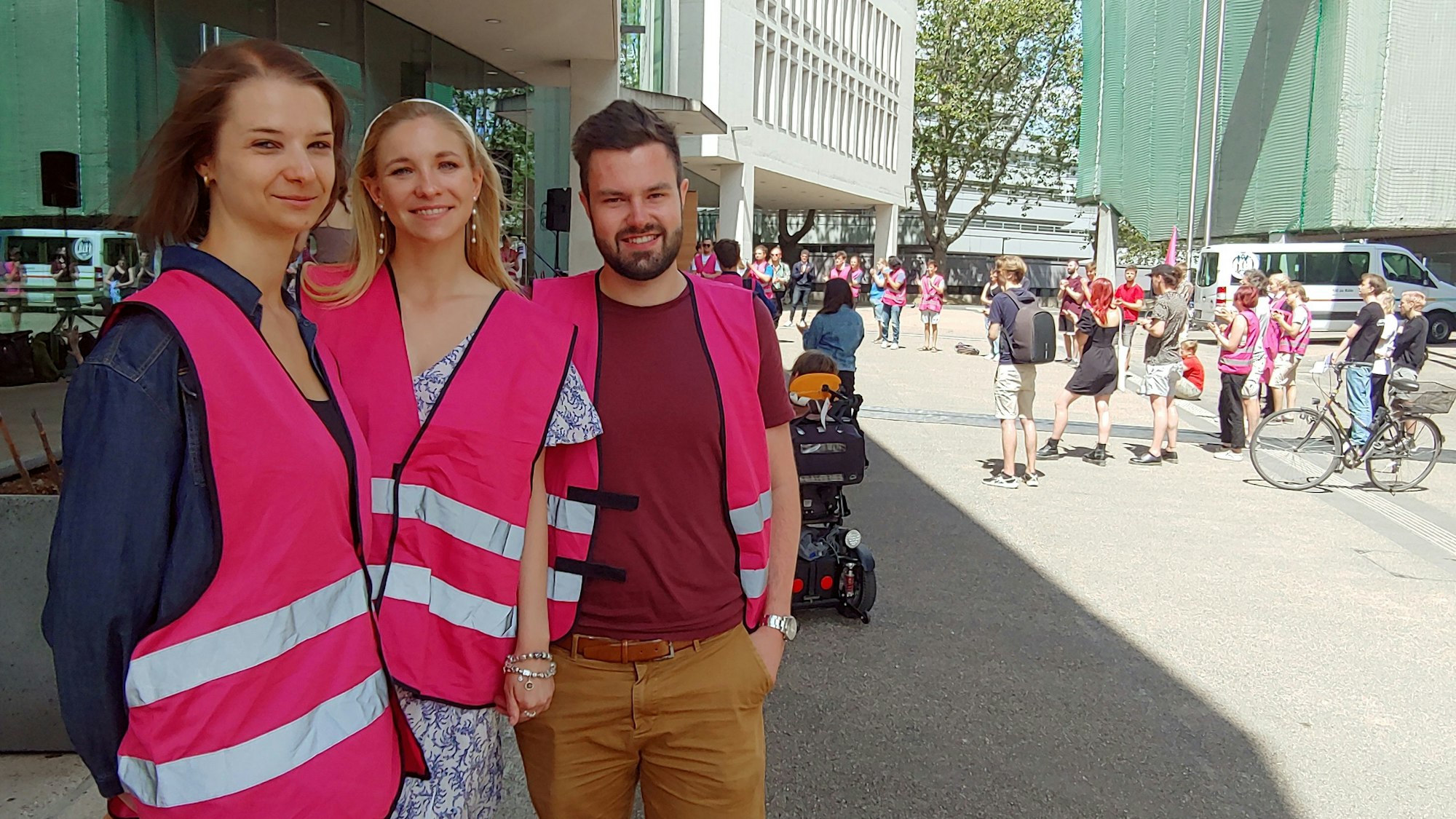 Zwei Frauenund ein Mann mit einer pinken Warnweste