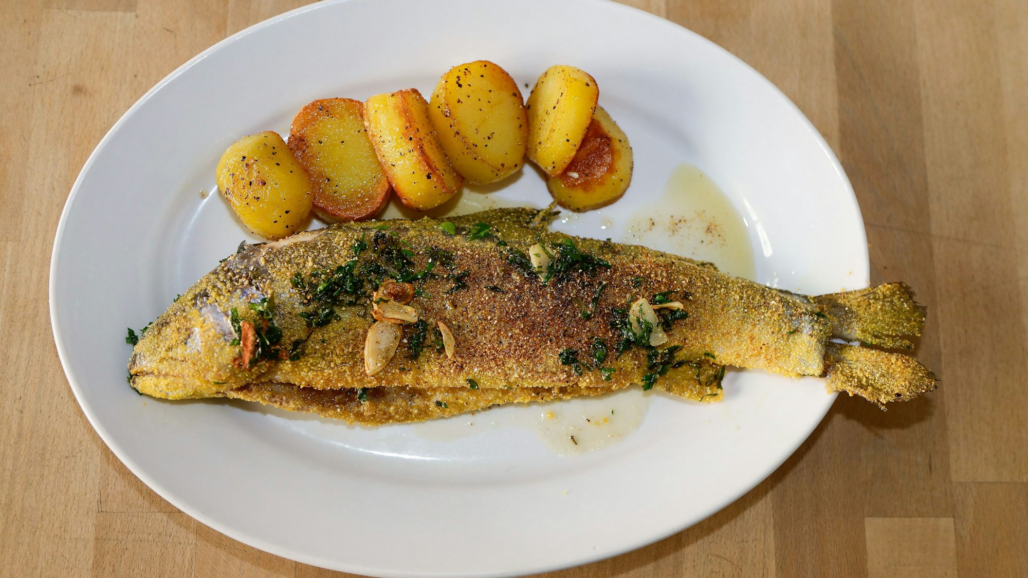 Hauptgang des Sommermenüs ist eine gebratene Forelle mit Kartoffeln und Tomatensalat.