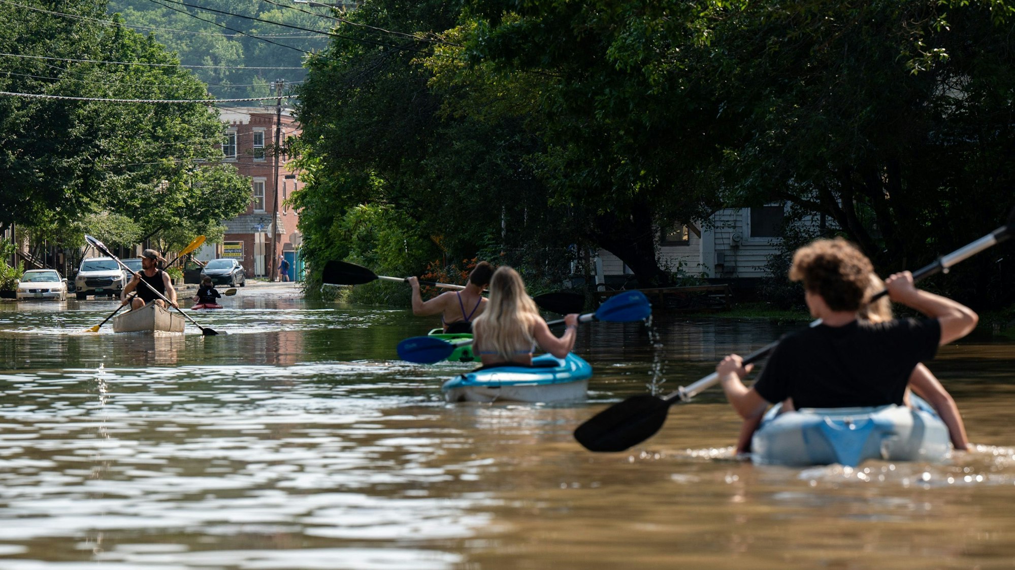 Viele Menschen sind mit Kajaks auf der überfluteten Straße unterwegs.