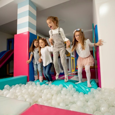 Gruppe von glücklichen kleinen Mädchen, die in eine Ballgrube springen.