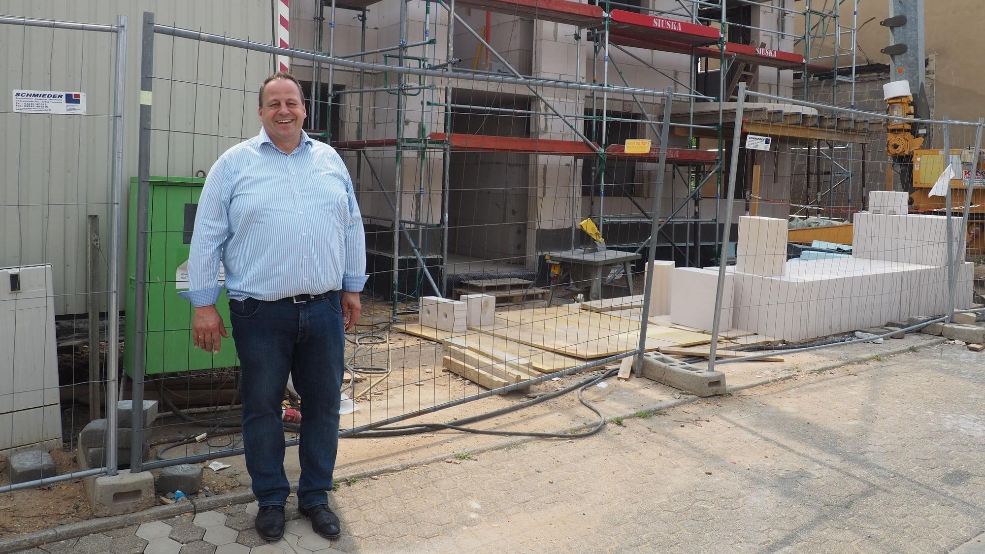 Ein Mann steht vor dem Rohbau eines Hauses