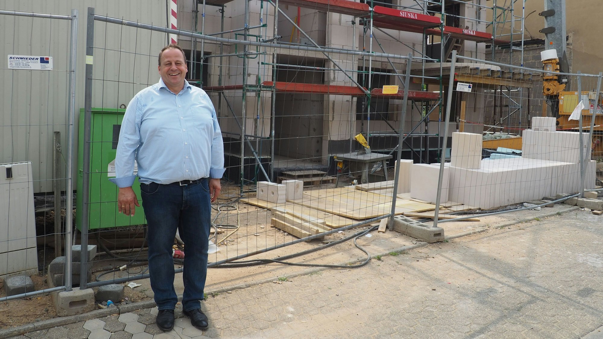 Ein Mann steht vor dem Rohbau eines Hauses