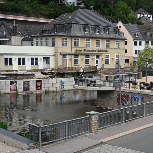 Das Bild zeigt das von der Flut 2021 zerstörte Hotel Friedrichs in Gemünd, davor der neue Nepomuk-Platz am Zusammenfluss von Urft und Olef.