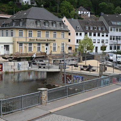 Das Bild zeigt das von der Flut 2021 zerstörte Hotel Friedrichs in Gemünd, davor der neue Nepomuk-Platz am Zusammenfluss von Urft und Olef.