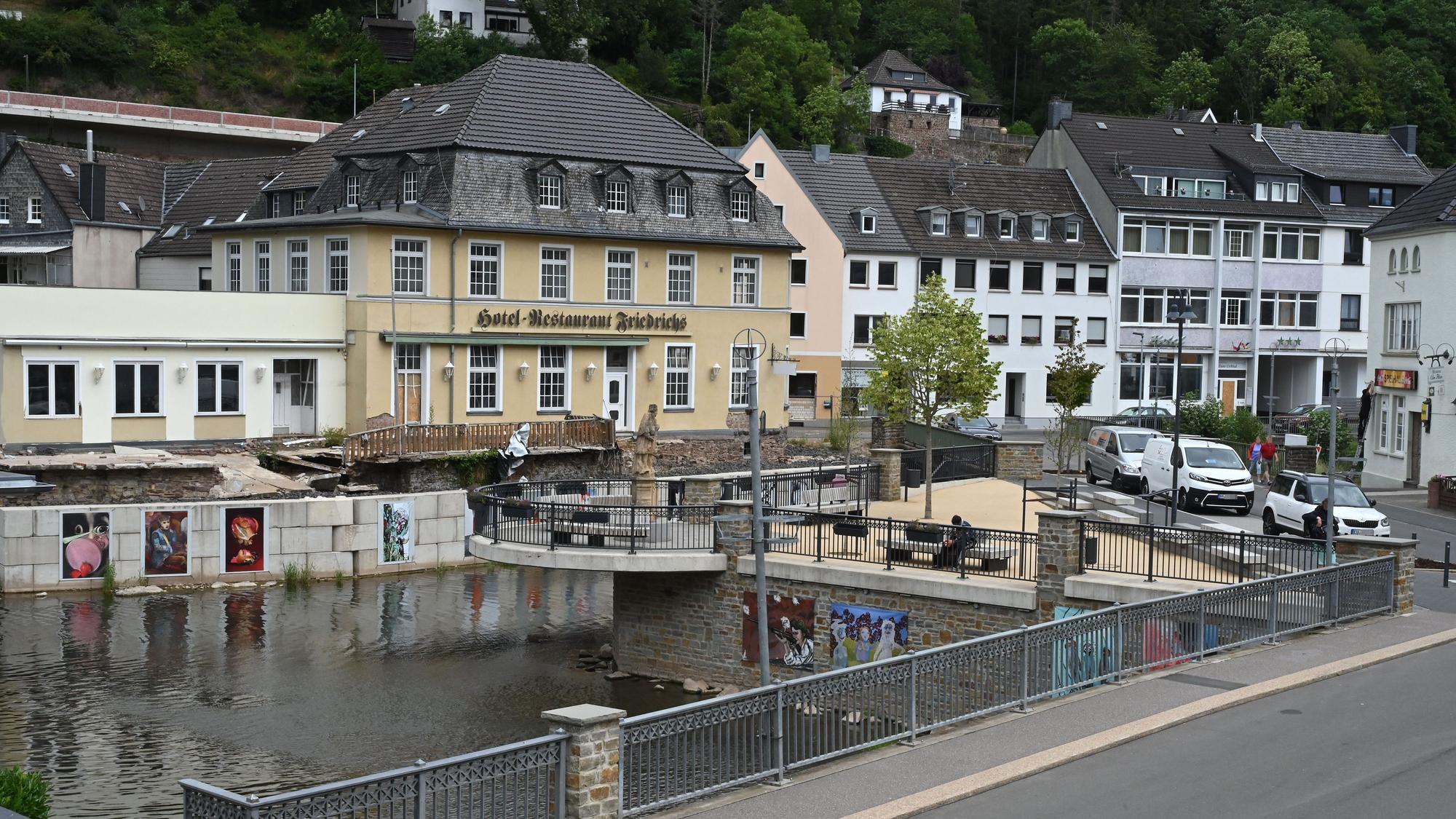 Das Bild zeigt das von der Flut 2021 zerstörte Hotel Friedrichs in Gemünd, davor der neue Nepomuk-Platz am Zusammenfluss von Urft und Olef.