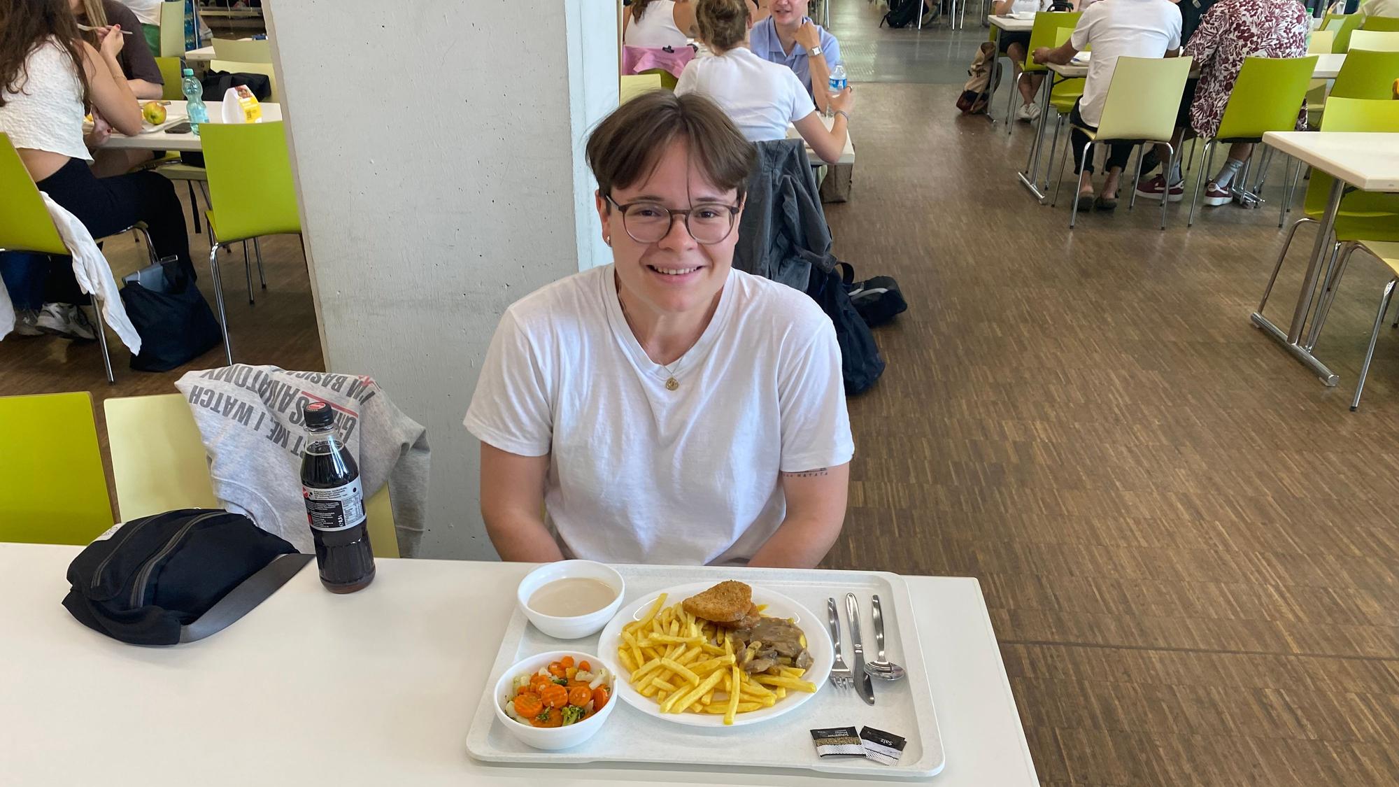 Auf dem Bild sieht man eine junge frau an einem Tisch sitzen.
