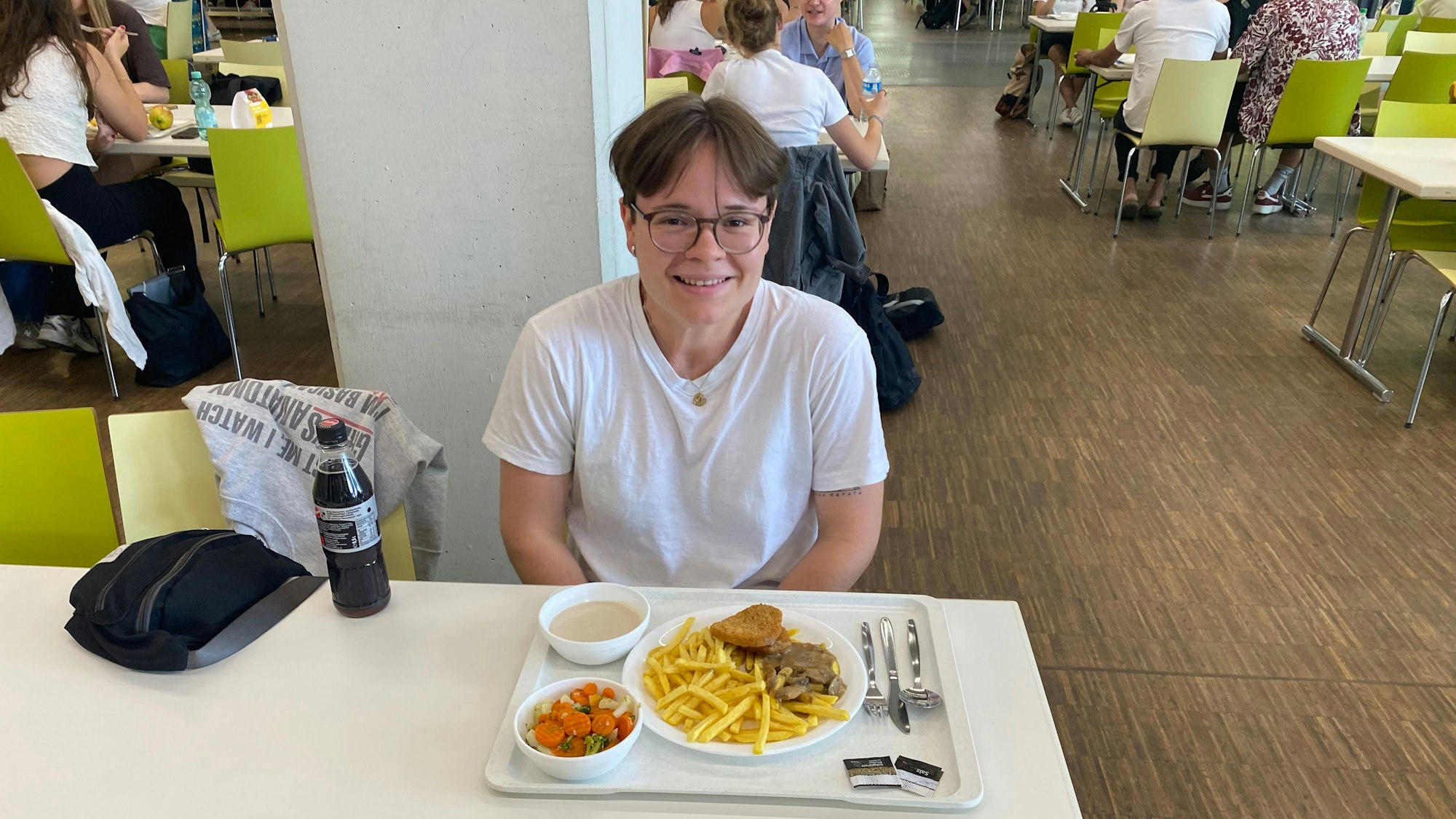 Auf dem Bild sieht man eine junge frau an einem Tisch sitzen.