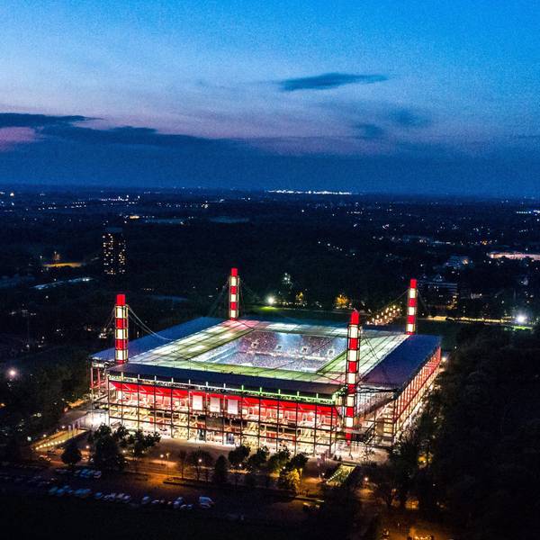 Außenansicht eines Fußballstadions während der Abenddämmerung, beleuchtet in den Farben Rot-Weiss