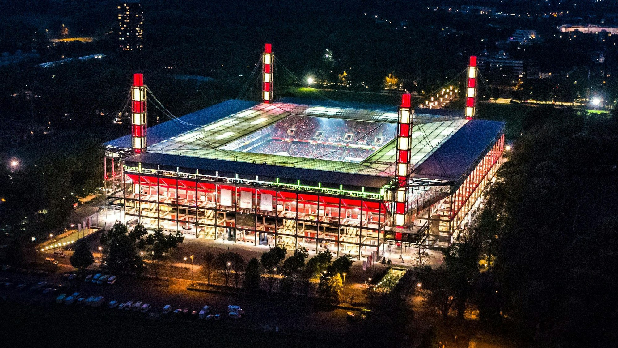 Außenansicht eines Fußballstadions während der Abenddämmerung, beleuchtet in den Farben Rot-Weiss