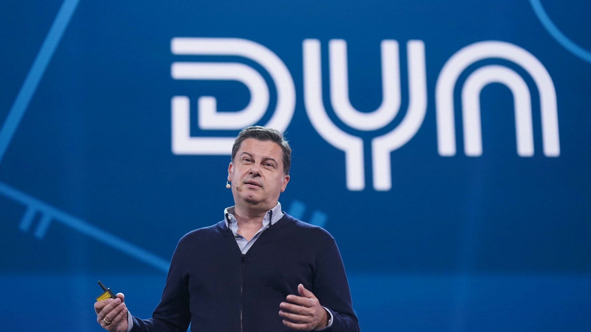 Christian Seifert steht auf einer Bühne vor dem Firmenlogo des Sport-Streaming-Dienstes Dyn