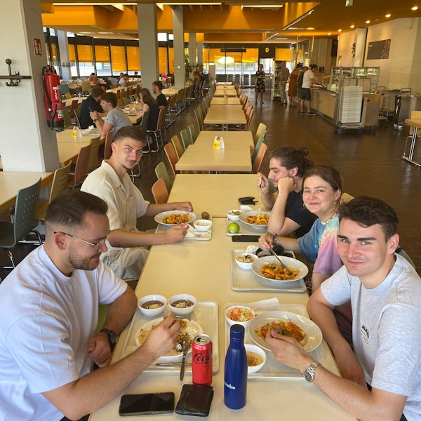 Auf dem Bild sieht man fünf junge Erwachsene beim Essen.