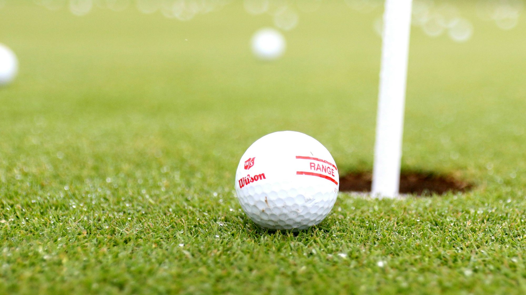 Das Foto zeigt einen Golfball, der kurz vorm Ziel - dem Loch - liegengeblieben ist.