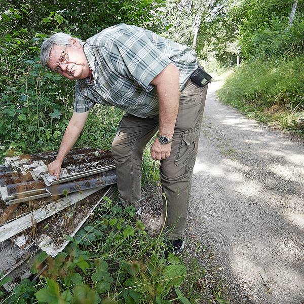 Harald Heinen sieht sich die am Wegesrand abgelegten Platten an.