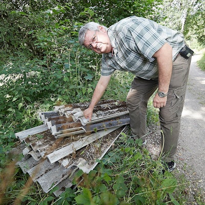 Harald Heinen sieht sich die am Wegesrand abgelegten Platten an.