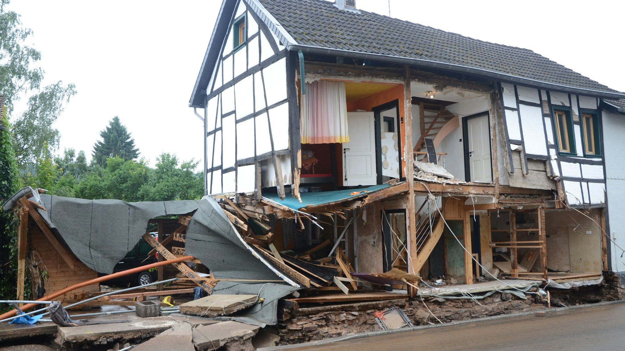 Das Bild zeigt ein Fachwerkhaus in Gemünd nach der Flutkatastrophe im Juli 2021. Das Wasser hat die Fassade weggerissen.