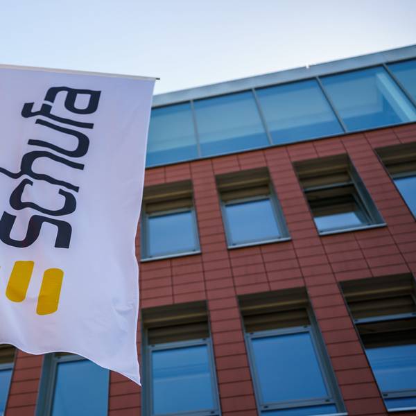 Eine Flagge mit dem Firmenlogo der Schufa, drei breiten gelben Querstreifen, flattert vor dem Geschäftssitz in Wiesbaden.
