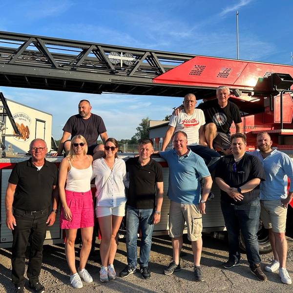 Eine Gruppe von Menschen vor einem Feuerwehrwagen.