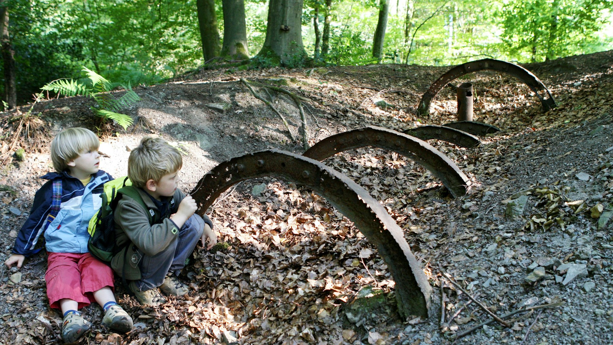 Kinder sintzen im Wald vor Bergbauspuren
