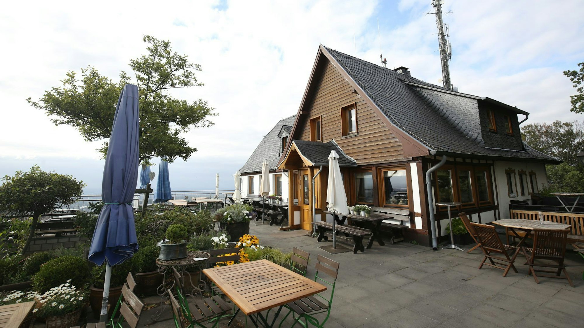 Vor einem Gasthaus stehen Tische und Stühle.