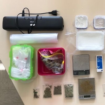 Die beschlangnahmten Gegenstände der Polizei sind auf einem Tisch ausgebreitet, darunter eine Machete, Marihuana und Amphetamine.
