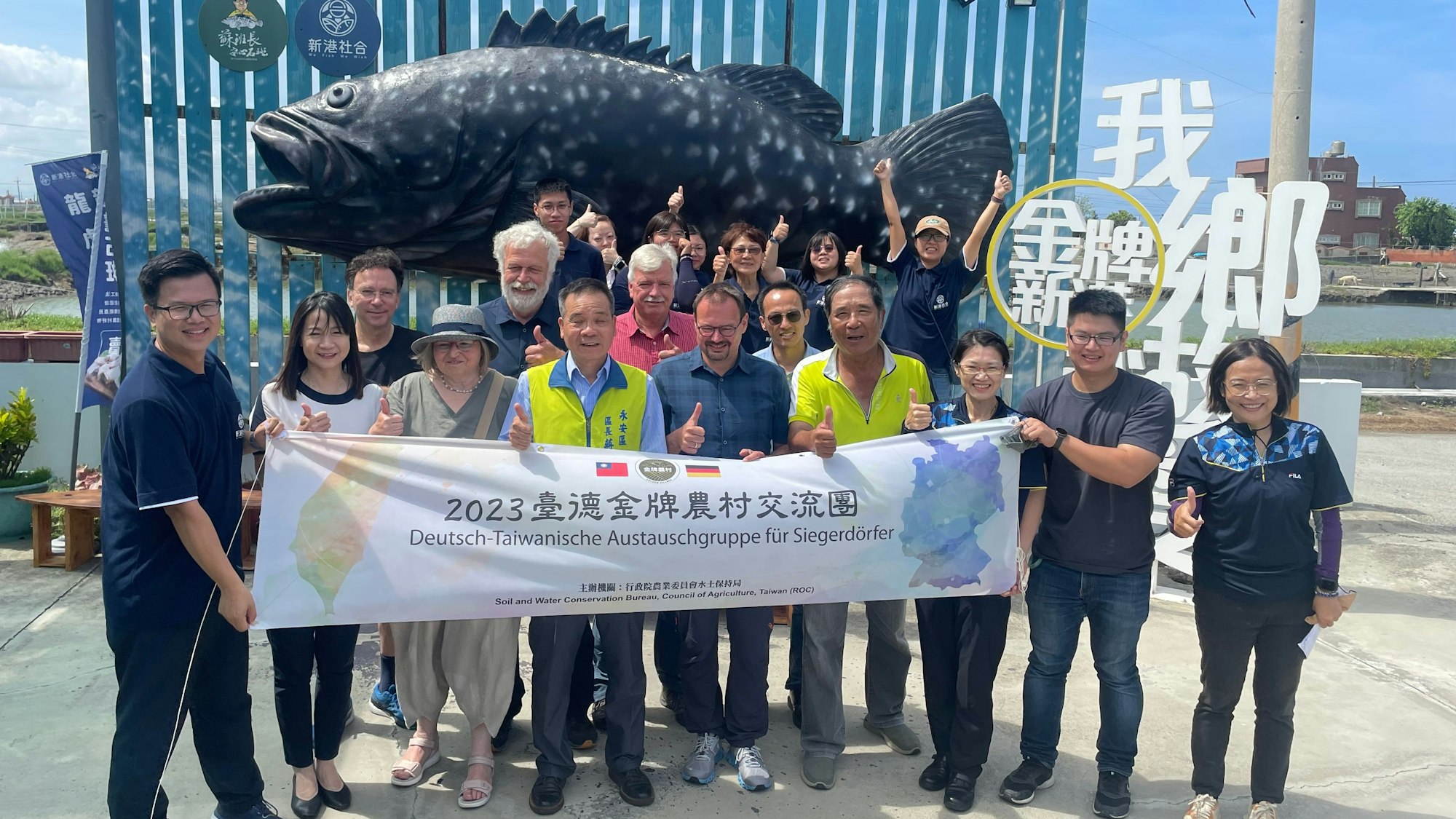 Die deutsche Delegation mit den beiden Benrothern posiert vor der Statue eines Zackenbarsch. Der Fisch ist im Süden des Inselstaats Taiwan eine wichtige Einnahmequelle.