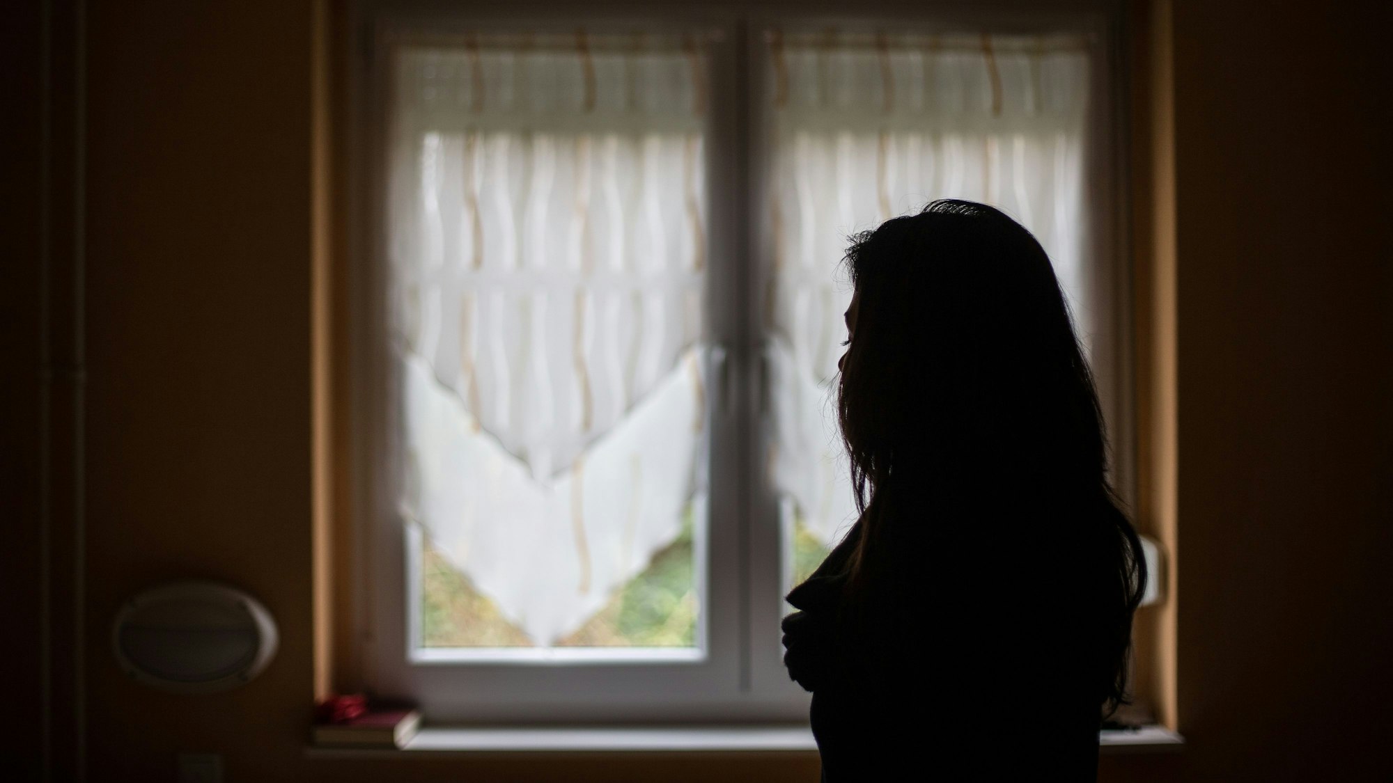 Eine Frau steht vor einem Fenster.