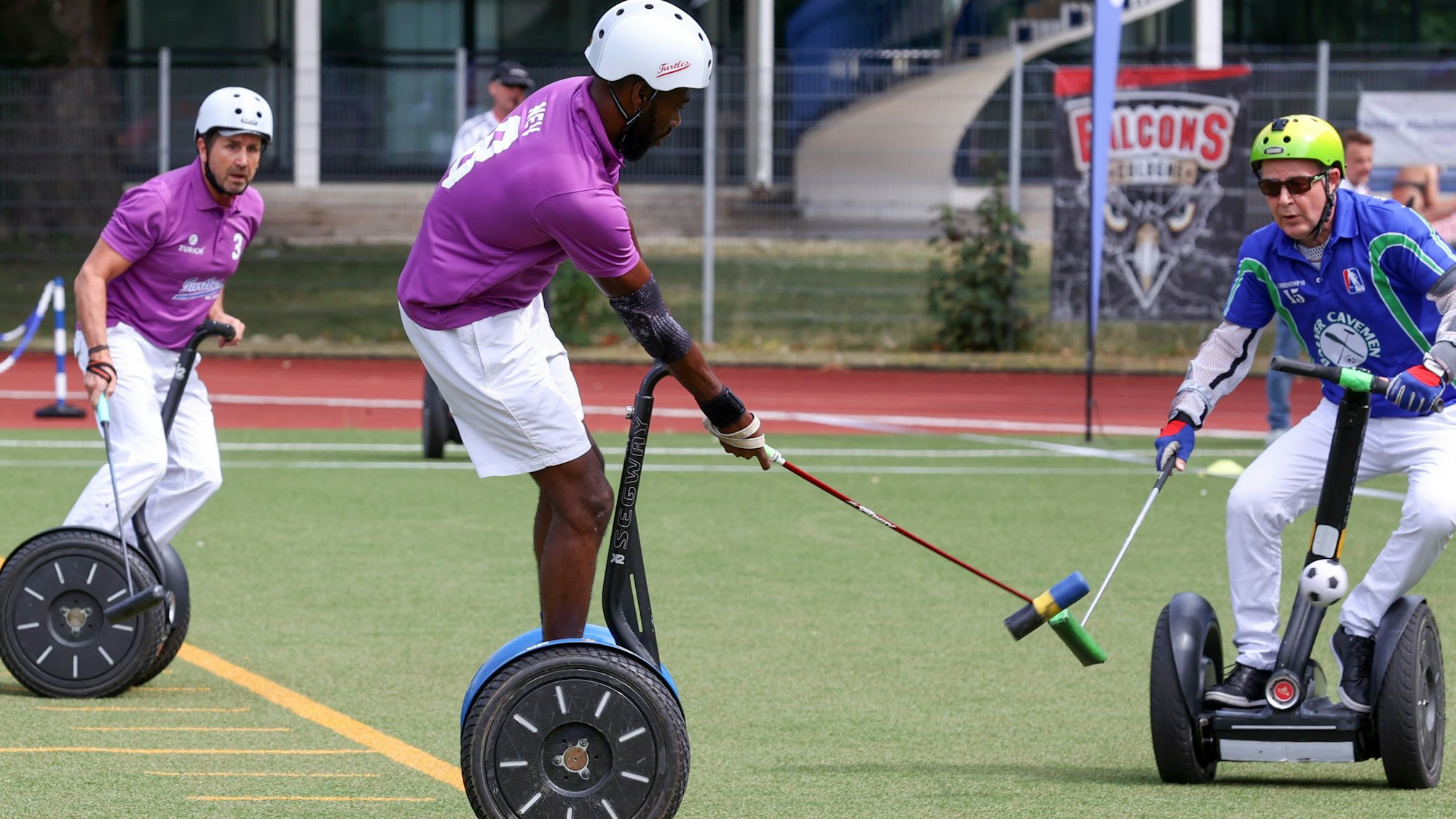 Zu sehen sind Spieler bei der Zehnten Weltmeisterschaft im Segway-Polo auf der Ostkampfbahn im Müngersdorfer Sportpark. Zu sehen sind von den Funky-Turtles (Violett) aus Lohmar links Werner Ludwig (3) und Nevin Roach (8).