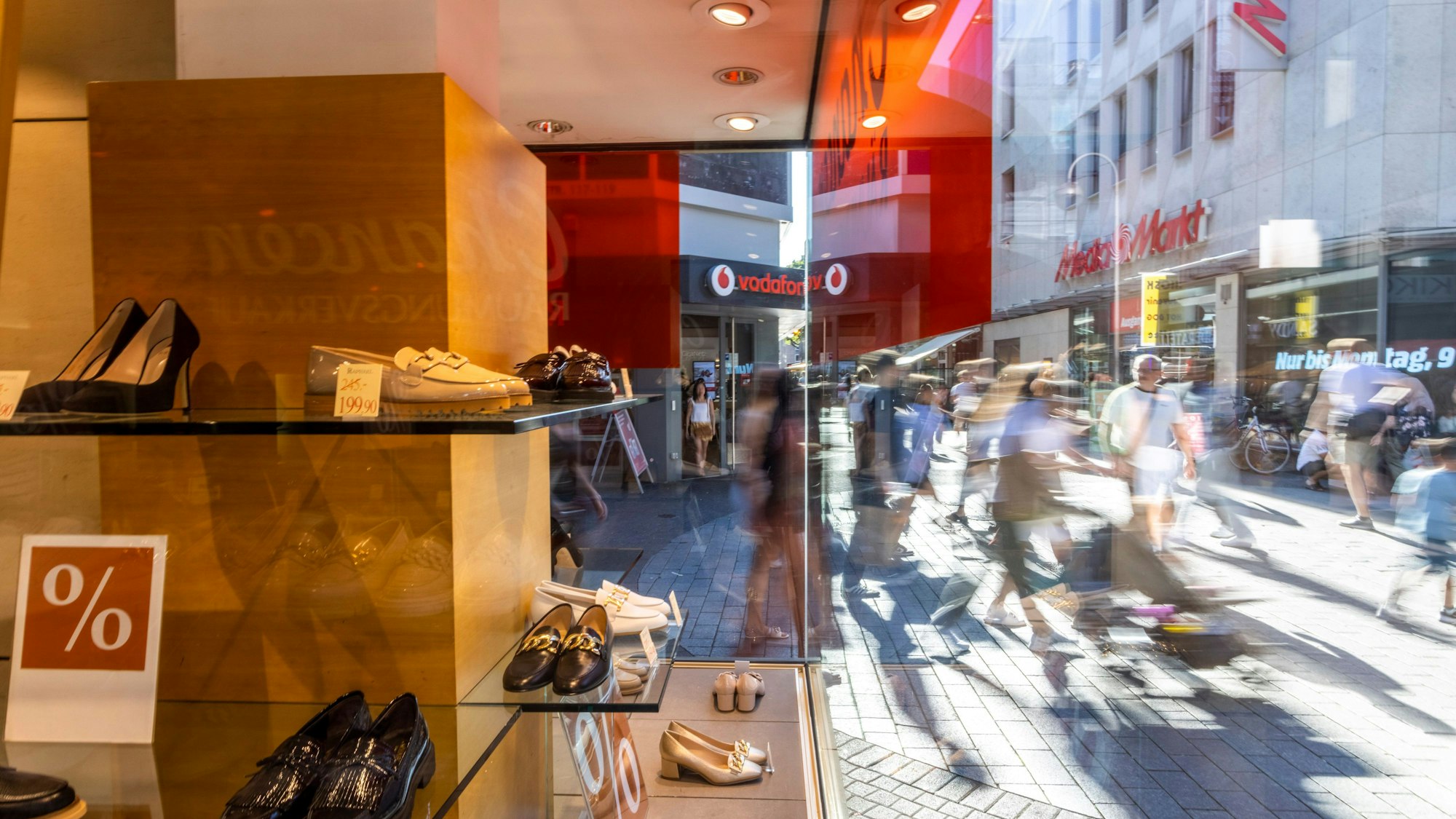 Ein Aufsteller mit dem Prozentzeichen auf einem Regal eines Schuhgeschäfts in der Kölner Innenstadt macht auf Rabatte aufmerksam.