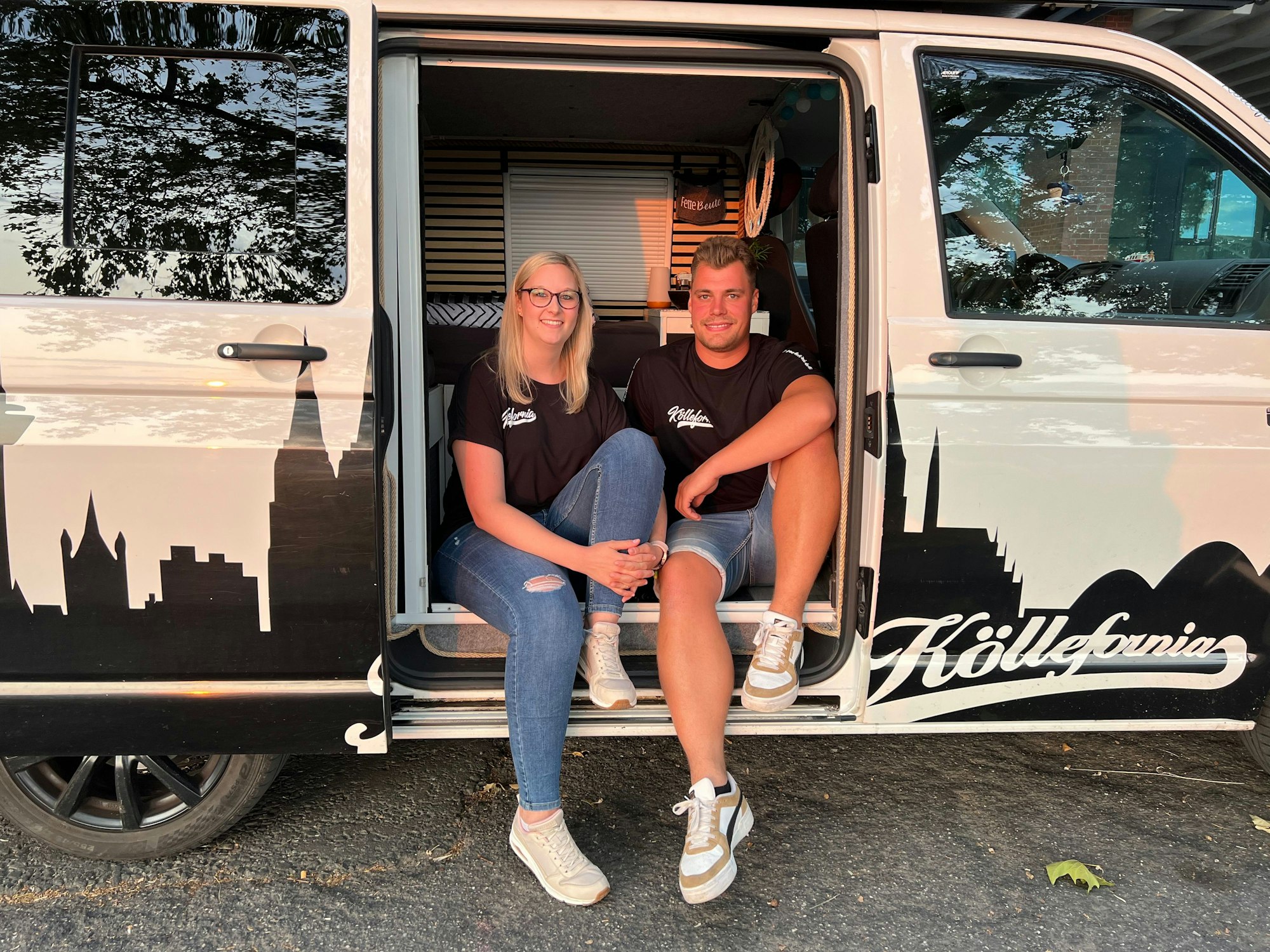 Tim Locke und Verena Van der Vight sitzen am Seiteneingang ihres Vans.