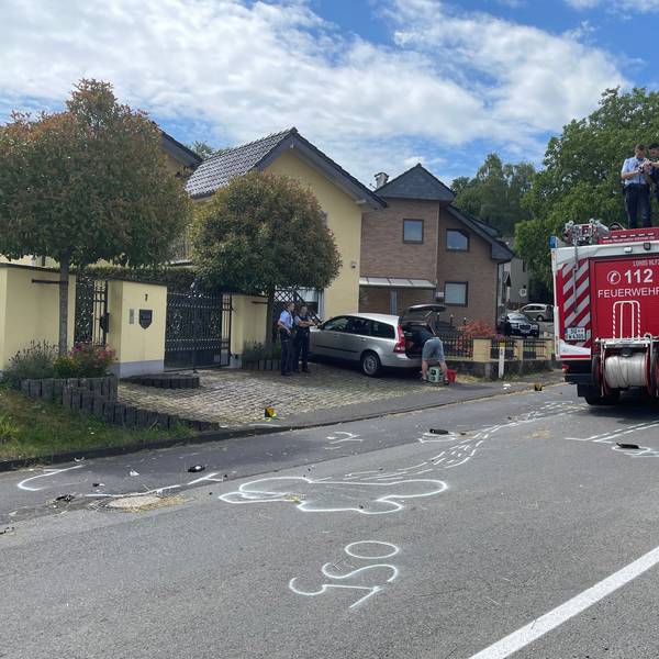Trümmerteile liegen nach dem Unfall auf der Fahrbahn verstreut, die Polizei fotografiert die Spuren vom Dach eines Löschfahrzeugs, Markierungen wurden auf die Fahrbahn gesprüht.