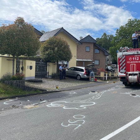 Trümmerteile liegen nach dem Unfall auf der Fahrbahn verstreut, die Polizei fotografiert die Spuren vom Dach eines Löschfahrzeugs, Markierungen wurden auf die Fahrbahn gesprüht.