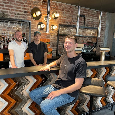 Drei junge Männer an einer Bar