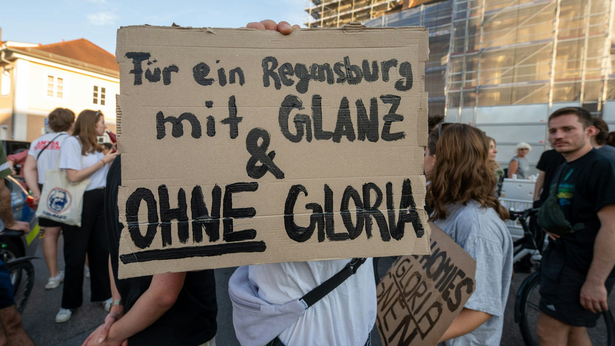 14.07.2023, Bayern, Regensburg: Ein Schild mit der Aufschrift "Für ein Regensburg mit Glanz & ohne Gloria" wird während einer Demonstration vor dem Fürstenschloss St. Emmeram in die Höhe gehalten. Zu Beginn der Regensburger Schlossfestspiele haben etwa 300 Menschen vor Schloss Thurn und Taxis demonstriert. Ihr Protest richtete sich unter anderem gegen umstrittene Aussagen der Hausherrin, Gloria Fürstin von Thurn und Taxis, unter anderem zum Thema Homosexualität. Foto: Armin Weigel/dpa +++ dpa-Bildfunk +++