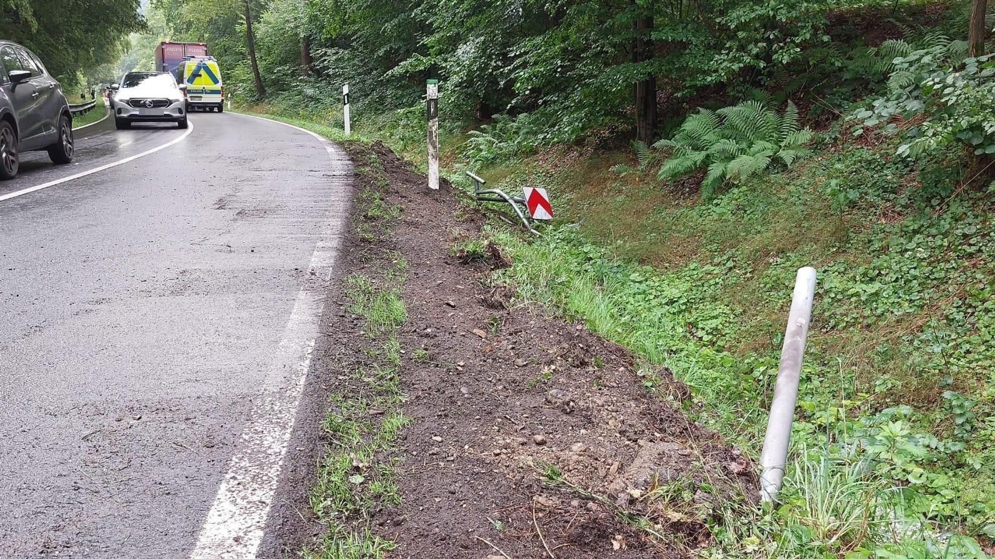 Ein beschädigtes Straßenschild liegt am Straßenrand im Gras.