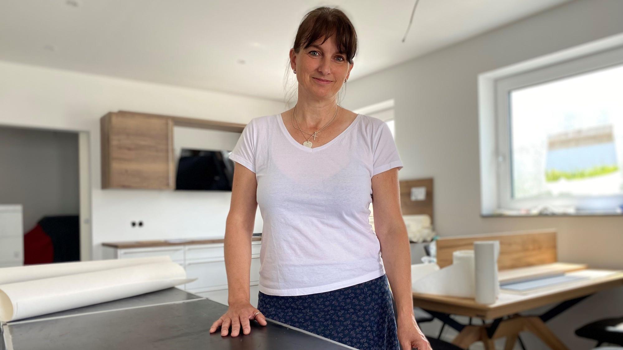 Eine Frau steht in der Küche und schaut in die Kamera.