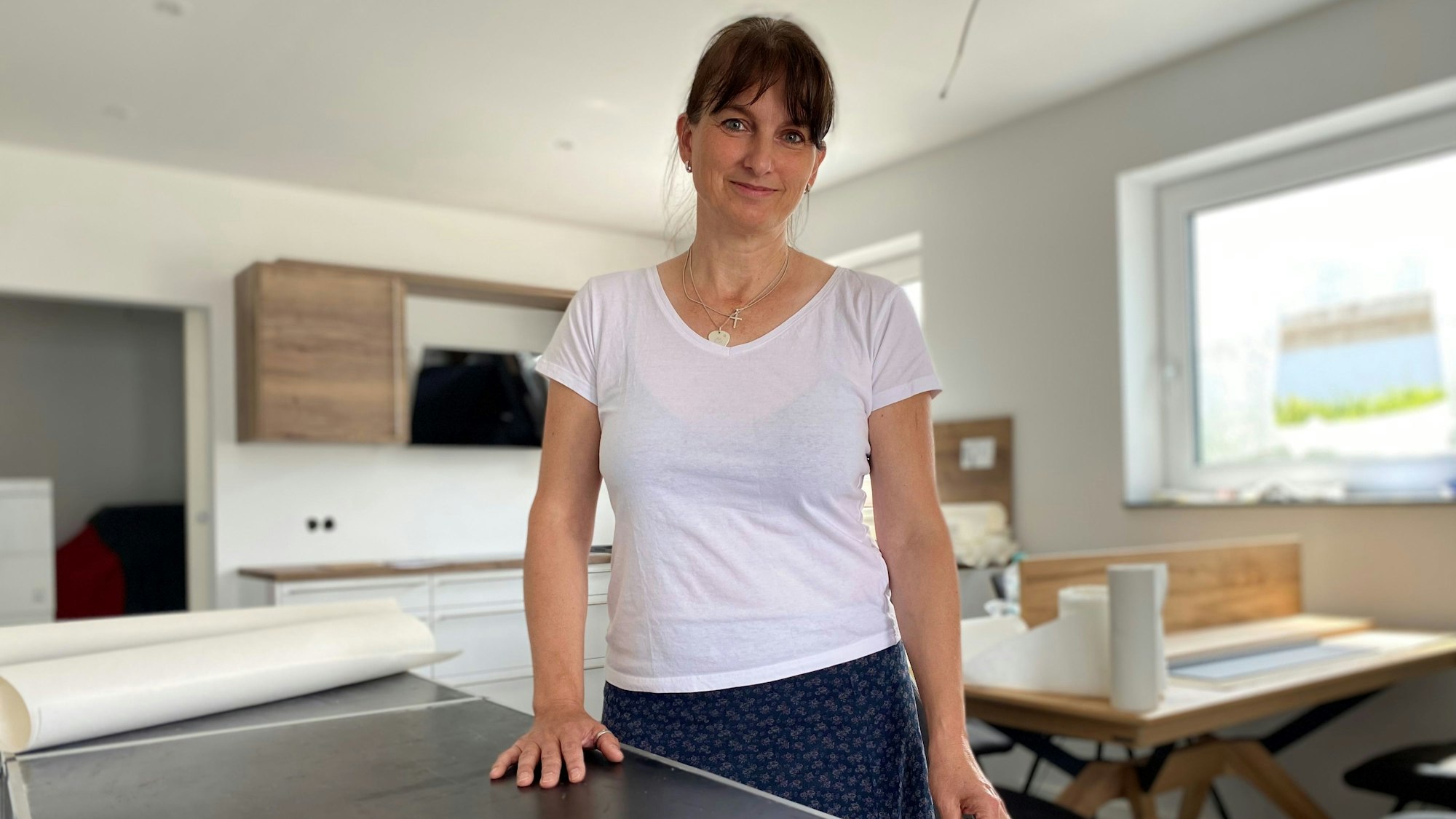 Eine Frau steht in der Küche und schaut in die Kamera.