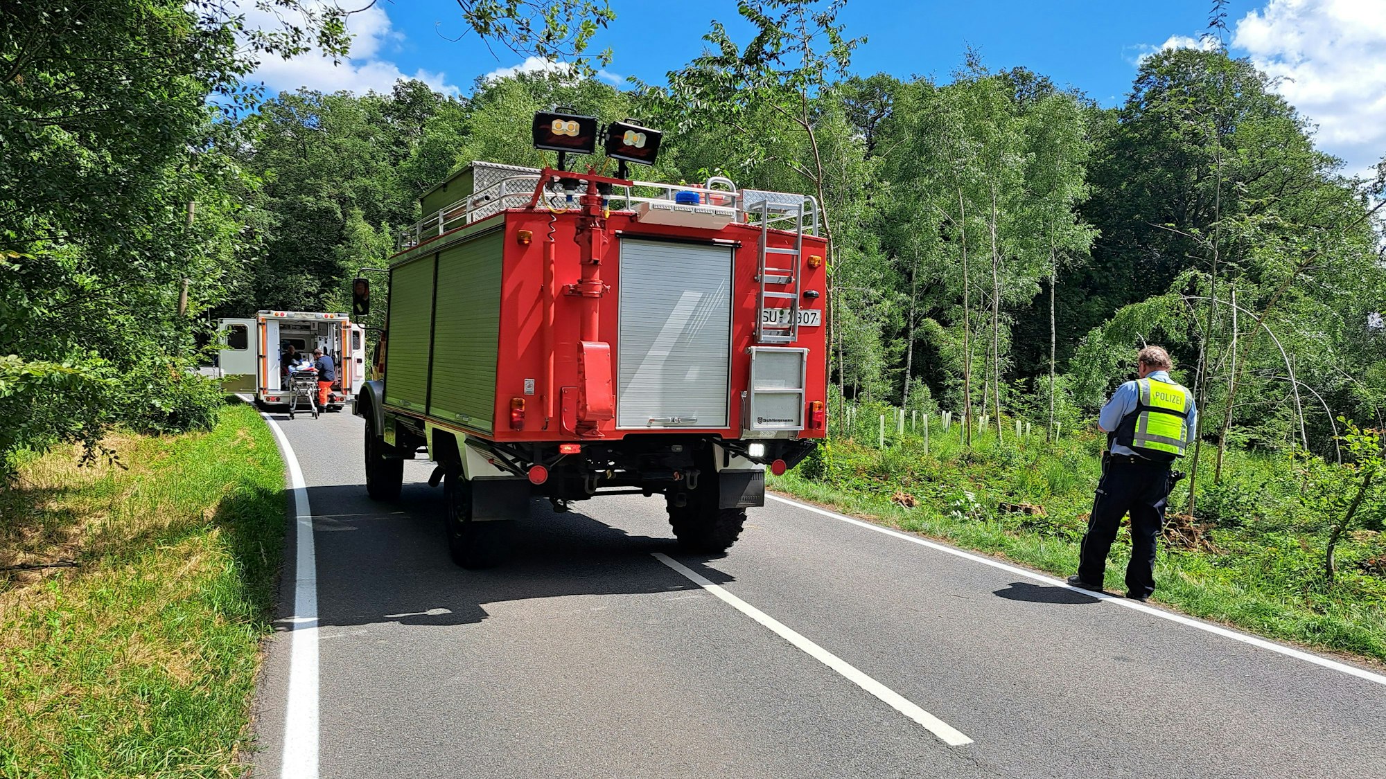 Einsatzkräfte an einer Unfallstelle auf einer Landstraße.