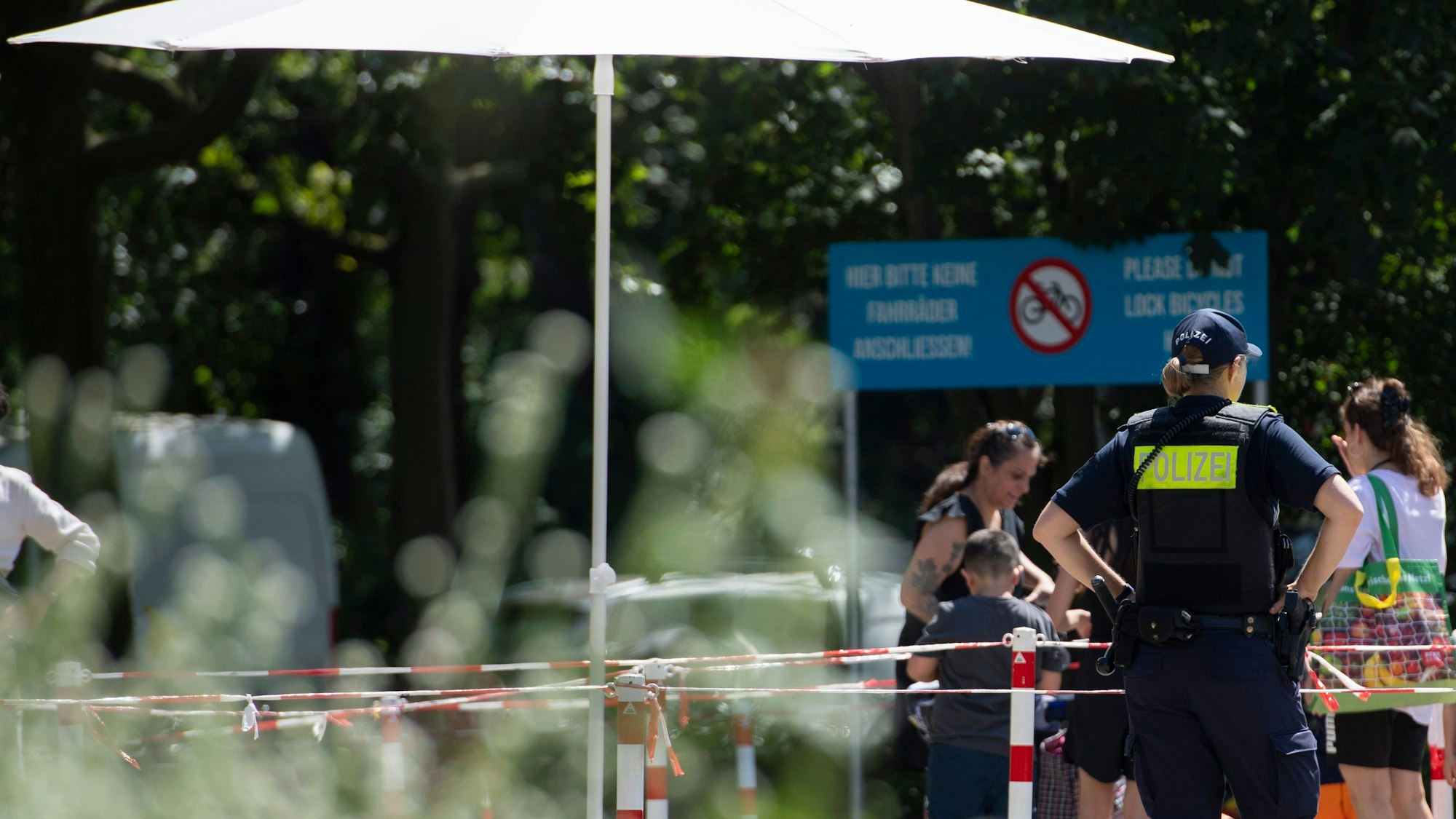 Eine Polizeibeamtin beobachtet am Prinzenbad in Kreuzberg die ankommenden Badegäste.