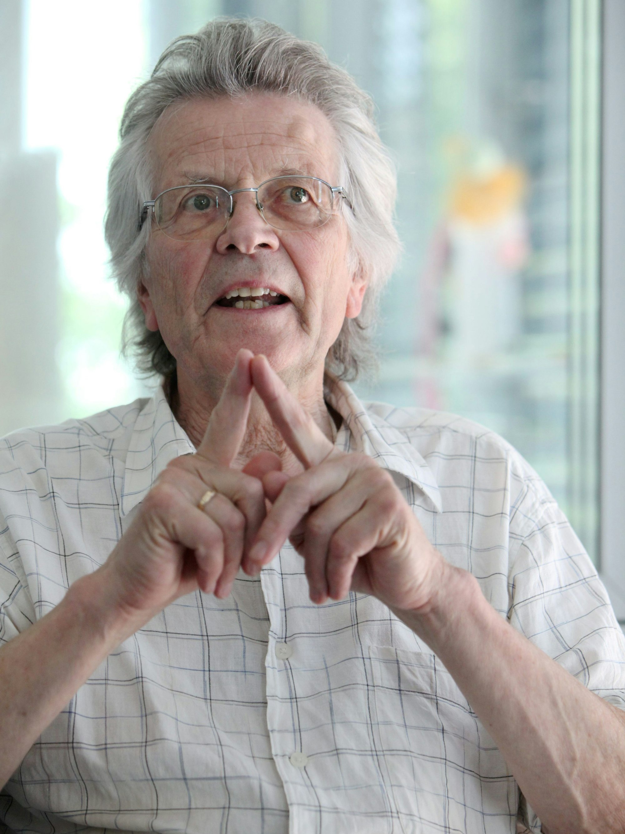 Der Architekt Peter Busmann aus Köln im Gespräch, seine Hände formen ein spitzes Dach.