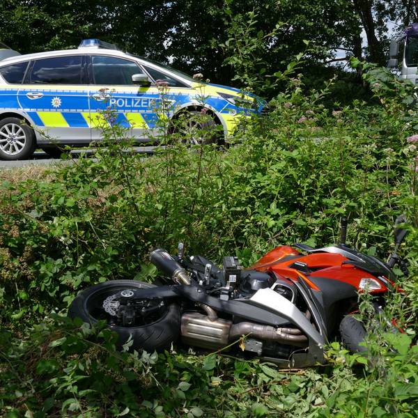 Ein Motorrad liegt in einem Straßengraben. Auf der Straße steht ein Polizeiauto.