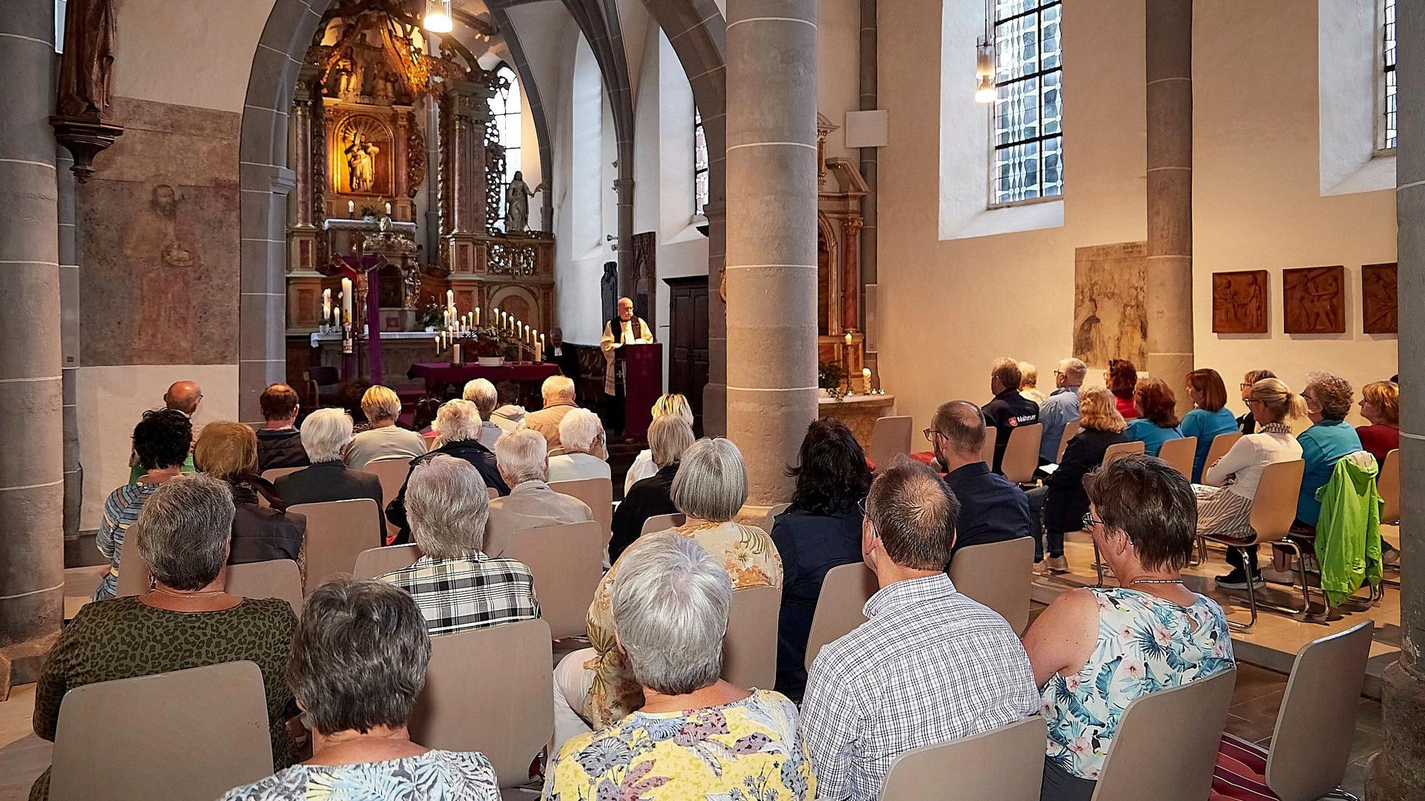 In der Pfarrkirche von Olef, die viele Monate wegen Flutschadens geschlossen war, sind rund 70 Teilnehmer zu sehen, die auf Stühlen sitzen und eine ökumenische Andacht feiern.
