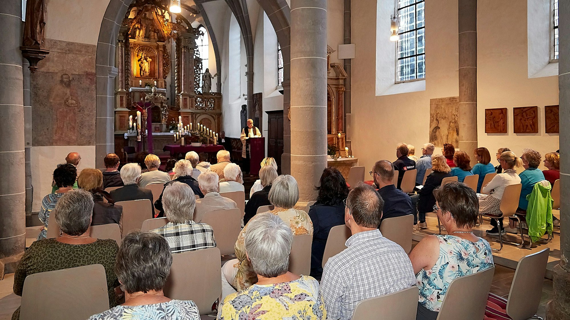 In der Pfarrkirche von Olef, die viele Monate wegen Flutschadens geschlossen war, sind rund 70 Teilnehmer zu sehen, die auf Stühlen sitzen und eine ökumenische Andacht feiern.