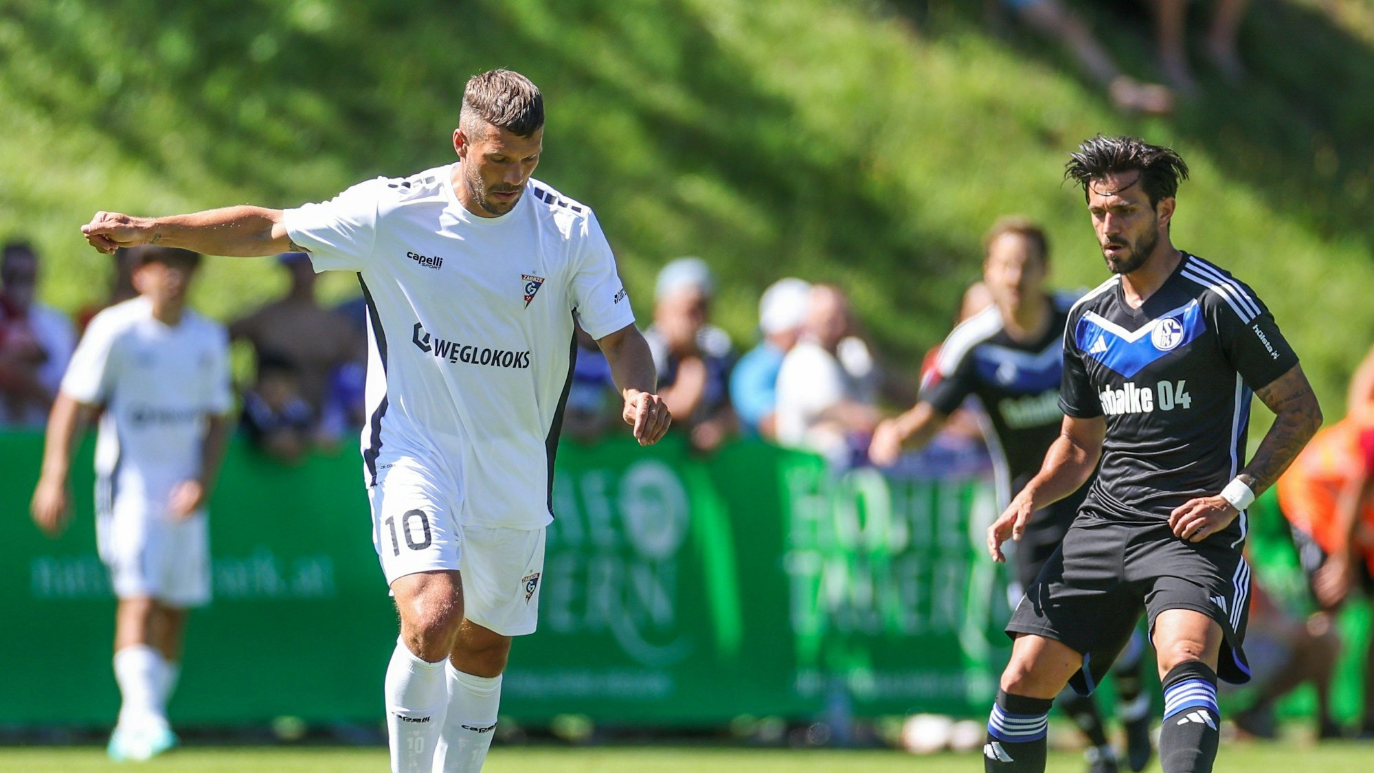 Lukas Podolski im Duell mit Schalkes Danny Latza.