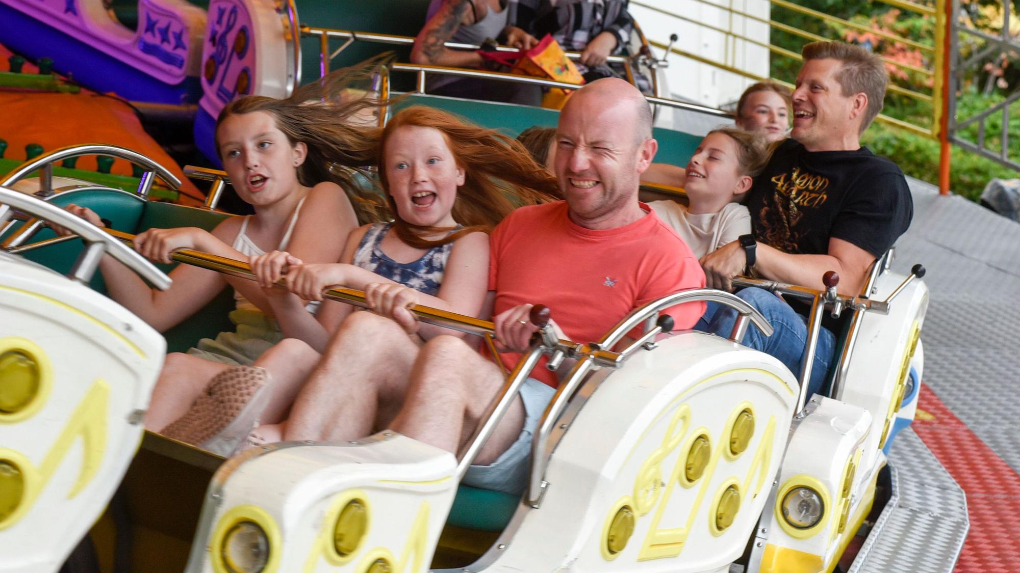 Kinder und Erwachsene fahren auf der Kirmes mit der Raupenbahn.
