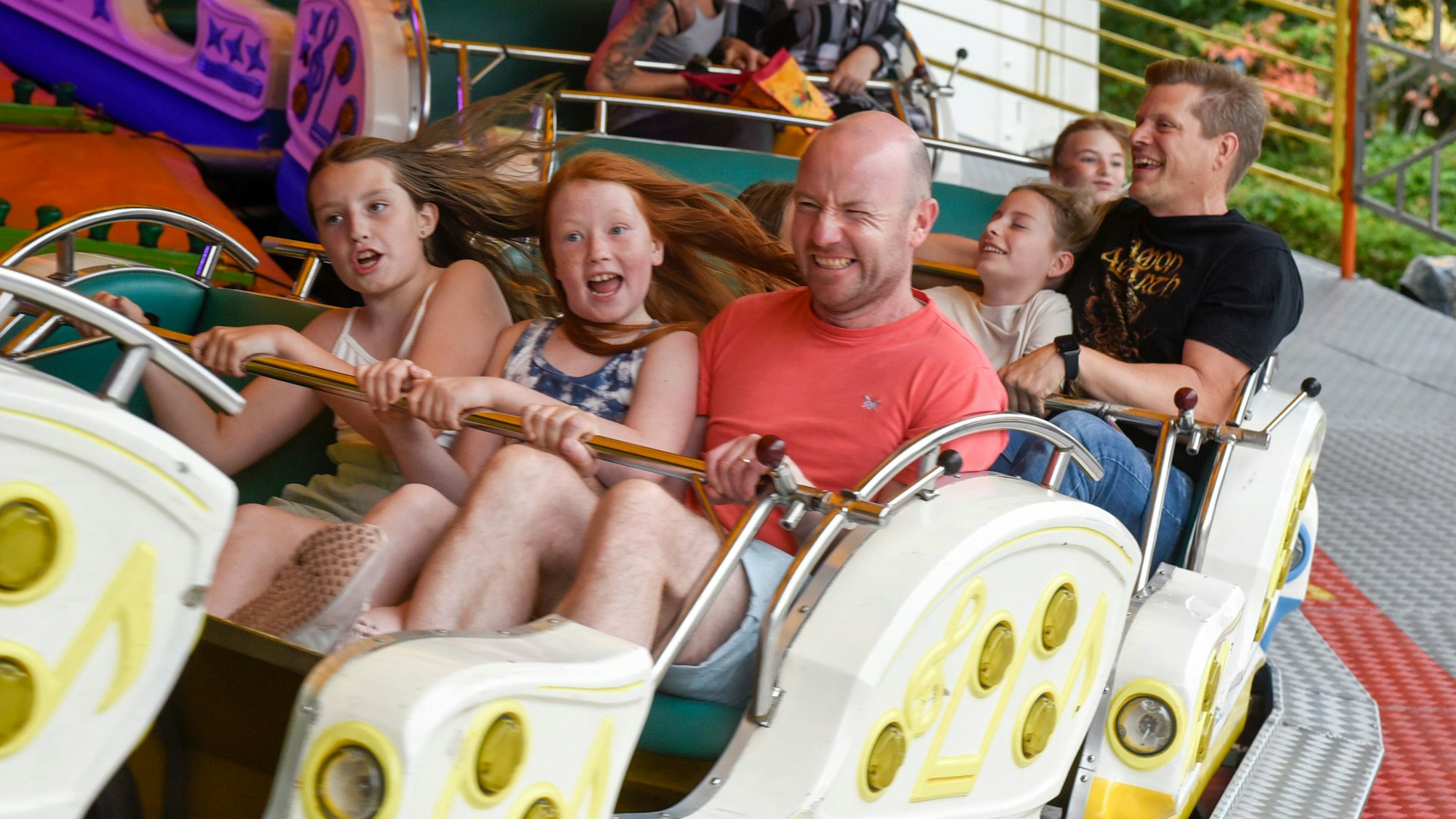 Kinder und Erwachsene fahren auf der Kirmes mit der Raupenbahn.
