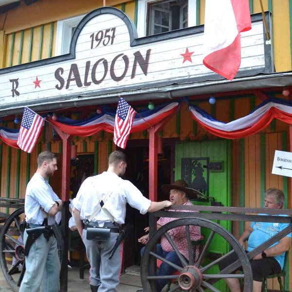 Männer stehen vor einem Wildwest-Saloon.