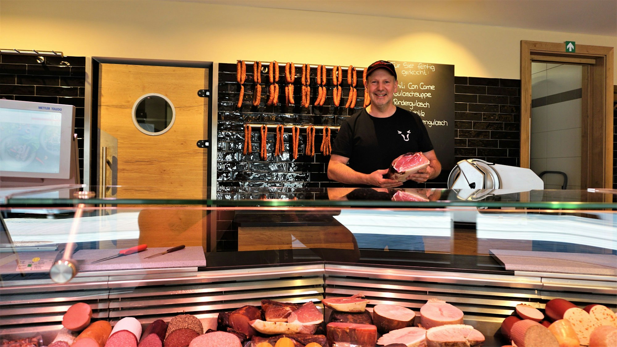 Ein Metzger inmitten von Fleischwaren hinter seiner Theke.