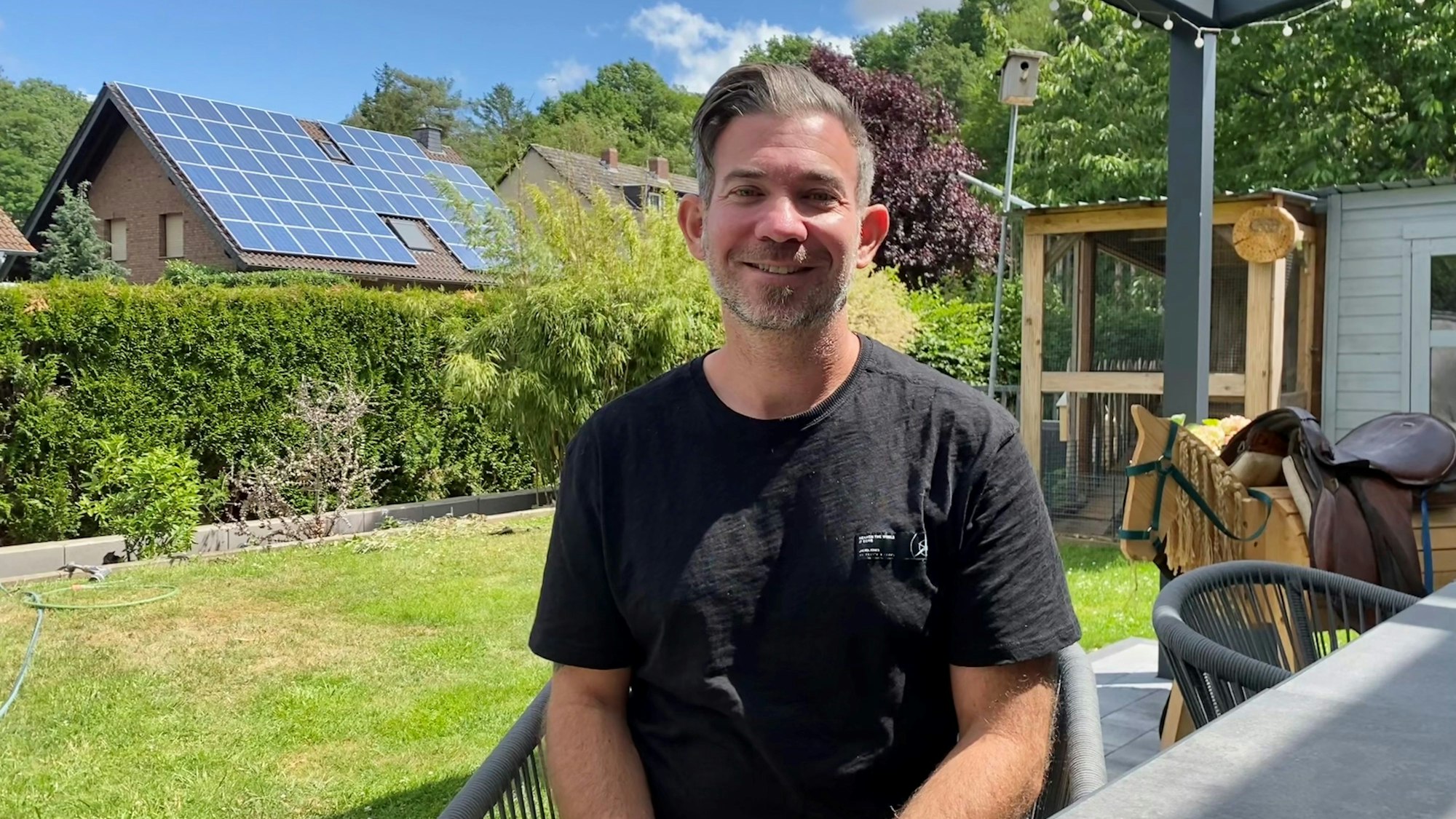 Ein Mann sitzt auf einem Stuhl in seinem Garten.